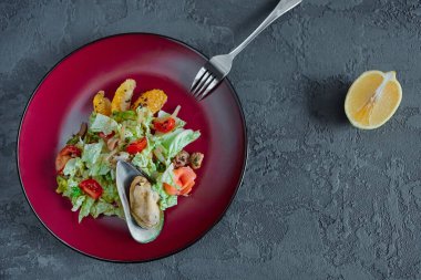 Gri desenli arka planda yuvarlak bir tabakta turunçgilli deniz ürünleri salatası..