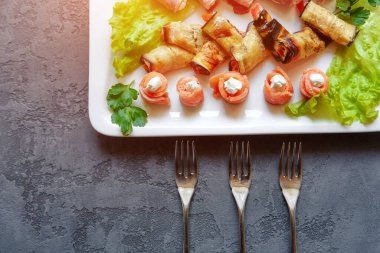 Soğuk mezeler, kanepeler ve rulo balıklar, patlıcan ve jambon, taze otlarla süslenmiş..