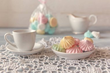 Pastel gölgeli çok renkli kremalar ve açık ahşap bir arka planda bir sürahi. Kahvaltının yanında çay ya da kahve konsepti, ev konforu ve şefkat. Yakın çekim, seçici odaklanma.