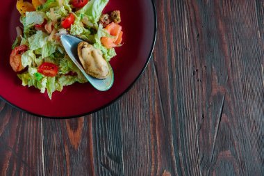 Gri desenli arka planda yuvarlak bir tabakta turunçgilli deniz ürünleri salatası..