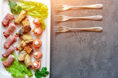 Soğuk mezeler, kanepeler ve rulo balıklar, patlıcan ve jambon, taze otlarla süslenmiş..