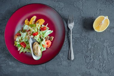 Gri desenli arka planda yuvarlak bir tabakta turunçgilli deniz ürünleri salatası..