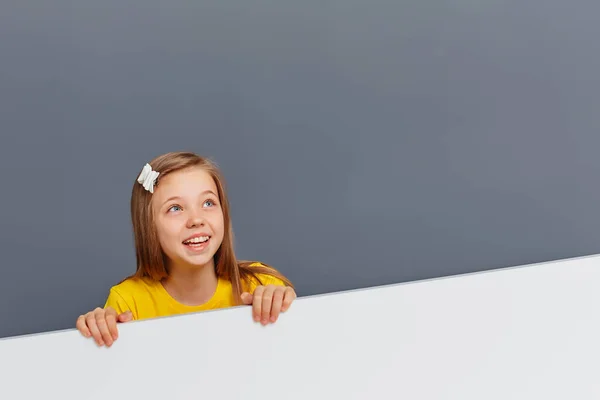 Menina Bonito Atrás Uma Placa Branca Com Uma Expressão Engraçada — Fotografia de Stock