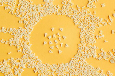 Parlak sarı bir zemin üzerine alfabe harfleri şeklinde yapıştır. Güneş şeklinde, ortada yazı var.