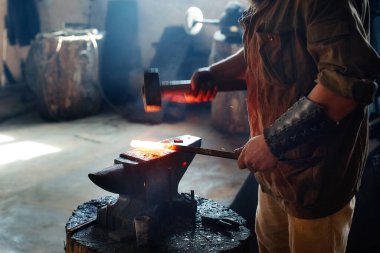 Demirci demir ocağında çekiçle çalışan bir demirci..