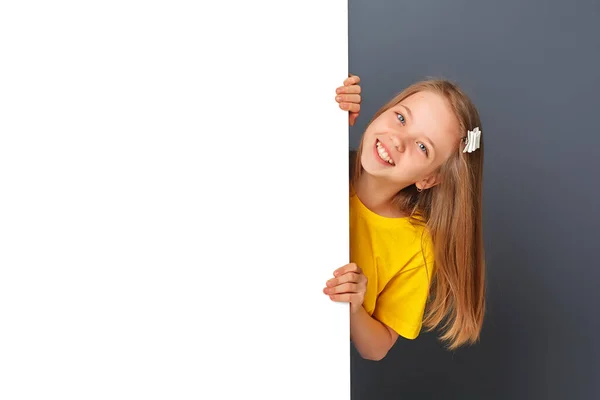 Vtipné Teen Dívka Žlutém Oblečení Vypadá Přes Bílou Stěnu Znamení — Stock fotografie