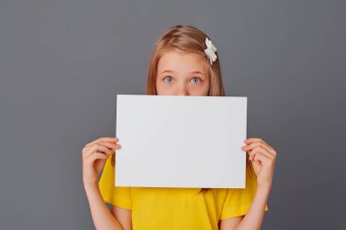 Sarı tişörtlü genç kız elinde boş beyaz kağıt tutuyor, mesaj için yer var, kopyalama alanı var..