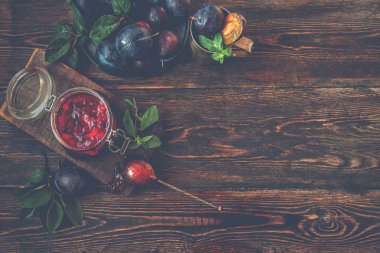 Bir kavanozda erik sosu ve bir masada mavi olgun erik. Sağlıklı, organik, ev yapımı yiyecekler. Tonlu görüntü. Üst te. Kopyalama alanı.