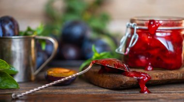 Bir kavanozda erik sosu ve bir masada mavi olgun erik. Sağlıklı, organik, ev yapımı yiyecekler. Tonlu görüntü.