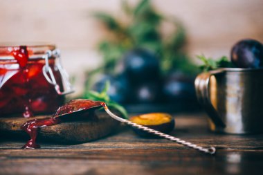 Eski ahşap bir masada ev yapımı erik reçeli ve taze erik meyvesi. Sonbahar vejetaryeni, vejetaryen yemekleri. Seçici odak.