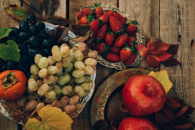 Taze nar, üzüm ve çilek yaprakları ile eski bir vintage tabakta. Rustik ahşap arka planda. Metin için boş alan. Üst te. Tonlu görüntü.