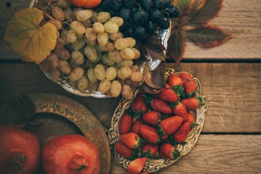 Sarı yaprakları, kırmızı taze nar, üzüm ve çilek ile Sonbahar arka plan. Kopya alanı ile yaşlı ahşap güz hasat. Sezonluk teklifler ve tatil kartpostalı için maket, en iyi görünüm.