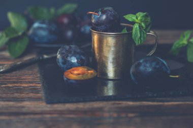 Siyah taş tabakta yaprakları olan erikler. Rustik yemek geçmişi. Taze organik meyveler. Sağlıklı yiyecekler. Tonlu görüntü. Metniniz için boş alan.