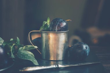 Siyah taş tabakta yaprakları olan erikler. Rustik yemek geçmişi. Taze organik meyveler. Sağlıklı yiyecekler. Tonlu görüntü. Metniniz için boş alan.