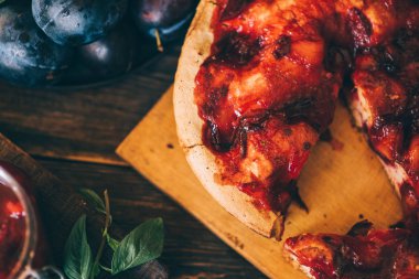 Koyu ahşap tahta arka plan üzerinde Rustik erik pasta. Sonbahar hasadı. Pasta ve yapraklı taze erik. Sağlıklı, organik gıda. Üst te. Tonlu görüntü.