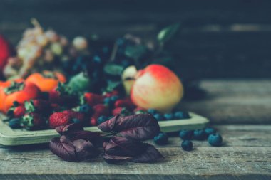 Eski bir ahşap masada çeşitli meyveler. Organik gıda. Taze çiğ meyve ve çilek. Autnum hasadı.