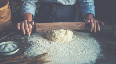 Bir oklava, un, tereyağı, buğday sivri ile rustik ahşap yüzey üzerinde ahşap bir masa üzerinde ev yapımı çiğ pasta.