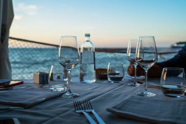 Güzel bir açık hava restoranı. Bulanık deniz manzaralı arka planda boş şarap kadehleri. Portonovo, İtalya 'da açık deniz terasında müşterileri bekleyen şık bir restoran masası..