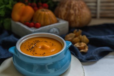Ekmek ile ev yapımı sonbahar butternut kabak çorbası. Beyaz ahşap arka plan üzerinde krema ve kabak çekirdeği ile kavrulmuş kabak ve havuç çorbası. Sağlıklı beslenme gıda kavramı. Kopya alanı. Tonlu görüntü.