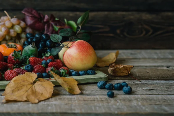 Vintage wooden tray and fresh fruits on wooden table. Fresh organic fruits and fall leaves. Autnum harvest. Toned vintage image with copy space.