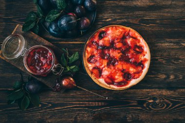 Koyu ahşap tahta arka plan üzerinde Rustik erik pasta. Sonbahar hasadı. Pasta ve yapraklı taze erik. Sağlıklı, organik gıda. Üst te. Tonlu görüntü.