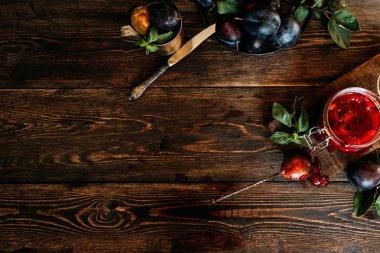 Bir kavanozda erik sosu ve bir masada mavi olgun erik. Sağlıklı, organik, ev yapımı yiyecekler. Tonlu görüntü. Üst te. Kopyalama alanı.