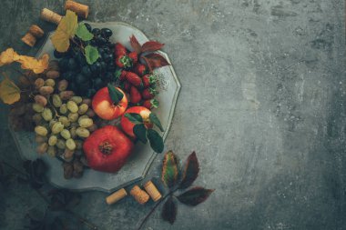 Taze nar, üzüm ve çilek yaprakları ile eski bir vintage tabakta. Rustik ahşap arka planda. Metin için boş alan. Üst te. Tonlu görüntü.