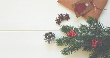 Noel tatili geçmişi. Çam ağacı dalları, kırmızı böğürtlenler, baharatlar ve kırsal ahşap masada hediyeler. Kış Xmas bayramı teması. Düz konum, üst görünüm, kopyalama alanı.