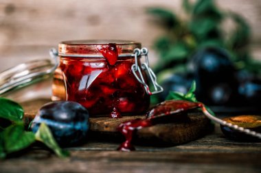 Tabakta taze organik erik ve rustik arka plan üzerinde cam bir kavanozda reçel. Autnum hasadı. Kopyalama alanı.