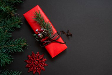 Noel hala hayattır. Kırmızı süslemeli bir hediye kutusu ve koyu bir arka plan. Lüks yeni yıl hediyesi. Noel hediyesi. Hediye kutulu Noel arkaplanı. Noel kutlaması.