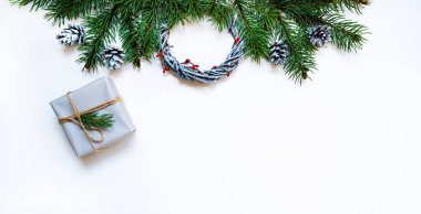 Noel sınırı. Çelenkler, kırmızı böğürtlen, köknar dalları, gri arka planda gri hediye kutusu ve çam kozalakları. Noel, kış, yeni yıl konsepti. Düz konum, üst görünüm, kopyalama alanı.