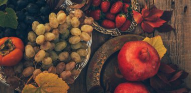 Sarı yapraklı sonbahar arkaplanı, kırmızı taze nar, üzüm ve böğürtlen. Fotokopi alanı ile eski ahşap üzerine sonbahar hasadı. Mevsimlik teklifler ve tatil kartpostalları için hazırlan..