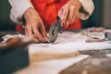 Kıdemli kadın restoran mutfakta hamur ile tagliatelle makarna yapma aşçı. Makarna yapıyorum. Restoranda makarna yapmak. Pancar, havuç ve ıspanak ile renkli çiğ sebze makarna.