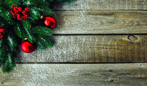 Christmas background for greeting card with Christmas tree branches, decoration and red balls, on rustic wooden table. Top view with copy space for text.