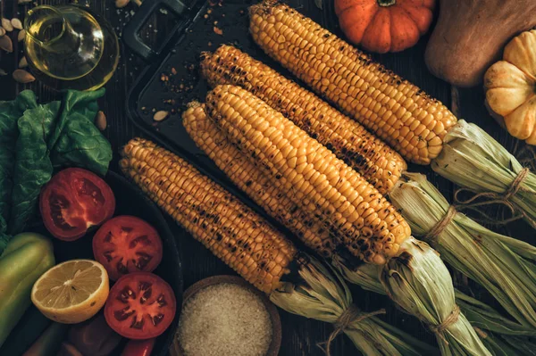 Summer or autumn food background. Ideas for barbecue and grill parties. Grilled corn, cheese on a dark wooden table. Healthy food, organic, bio, homemade food. Top view.