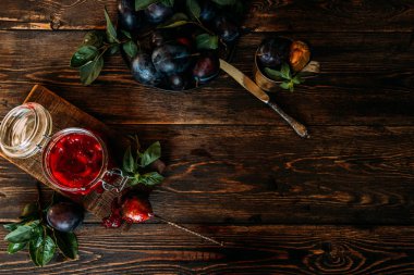 Eski ahşap bir masada ev yapımı erik reçeli ve taze erik meyvesi. Sonbahar vejetaryeni, vejetaryen yemekleri. Üst Manzara. Boşluğu kopyala.