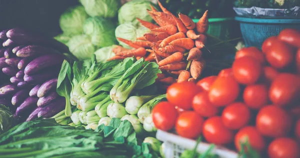 Asian food ingredients corner. Organic fresh agricultural product at farmer market. Fresh tomatoes, onions, eggplant, are packaged in simple containers and displayed for sale at an produce stand.