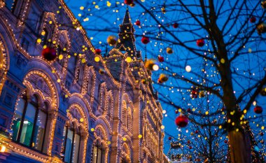 Ağaç gövdesindeki Noel ışıkları, yakın plan. Bulanık arka sokak, yılbaşı ışıklarıyla. Noel ve Yeni Yıl tatili geçmişi. Klasik renk tonu. Metnin için boşluk kopyala.