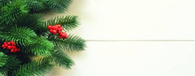 Köknar dalları ve kırsal ahşap arka planda kırmızı böğürtlenlerle Noel süslemesi. Noel, kış, yeni yıl konsepti. Düz konum, üst görünüm, kopyalama alanı.