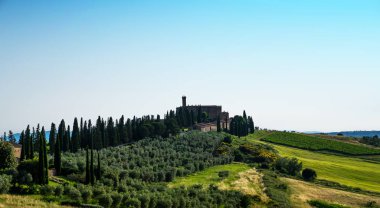 Tuscany rural günbatımı manzara. Kırsal çiftlik, selvi ağaçları, yeşil alan, güneş ışığı ve bulut. İtalya, Europe.