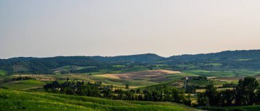 Toskana, kırsal alan. Yuvarlanan tepeler, taşra çiftliği, selvi ağaçları, sıcak günbatımında yeşil alan. İtalya, Avrupa.