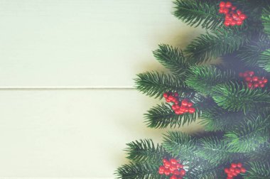 Köknar dalları ve kırsal ahşap arka planda kırmızı böğürtlenlerle Noel süslemesi. Noel, kış, yeni yıl konsepti. Düz konum, üst görünüm, kopyalama alanı.