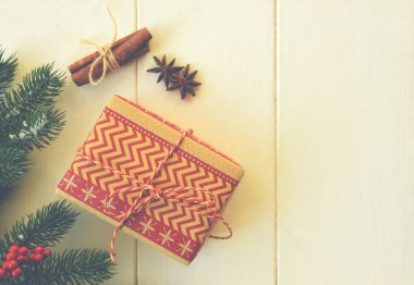 Noel tatili geçmişi. Çam ağacı dalları, kırmızı böğürtlenler, baharatlar ve kırsal ahşap masada hediyeler. Kış Xmas bayramı teması. Düz konum, üst görünüm, kopyalama alanı.