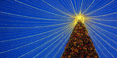 Geceleri dışarıda ışıklandırmalı Noel ağacı. Yeni Yıl Kutlaması. Kış mevsimsel tatillerinde Avrupa şehir caddesinde dekore edilmiş lüks.