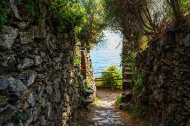 Dar bir ortaçağ sokağında mavi denizde ve gökyüzünde taş duvarlar var..