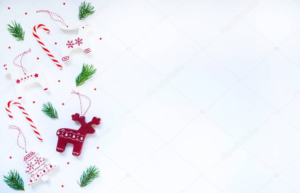 Christmas border with a red and white ornament, wintage wooden toys, fir branches, candy cane on a pastel background. Christmas, winter, new year concept. Top view with copy space for text.