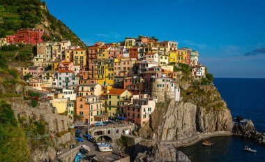Manarola, National Park Cinque Terre 'deki tipik İtalyan köyü, kayalıklardaki renkli renkli binalar, su üzerindeki balıkçı tekneleri, mavi gökyüzü arka planı, Liguria, İtalya