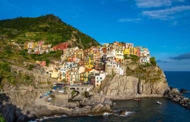 Manarola, National Park Cinque Terre 'deki tipik İtalyan köyü, kayalıklardaki renkli renkli binalar, su üzerindeki balıkçı tekneleri, mavi gökyüzü arka planı, Liguria, İtalya