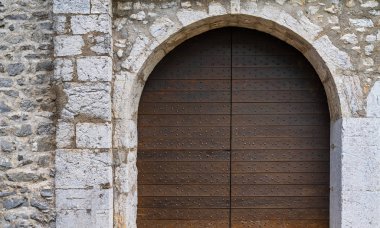 Ortaçağ kale kapısı. Eski taş kale duvarındaki antik ahşap kapı. Kilitli ahşap kapı, demir döşemeli..