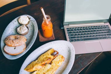 Laptoplu masa, içecek ve tabakla ekmek.